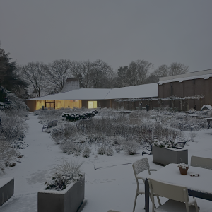 Sfeervolle winterse buitenruimte van Singer Laren, gefotografeerd door Nils Visser, met warm verlichte ramen van het museum op de achtergrond.